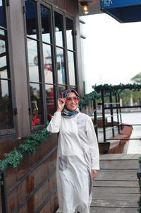 Smiling woman wearing hijab walking on footpath