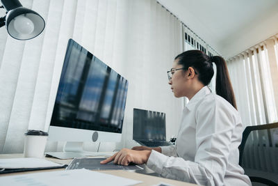 Side view of young woman using laptop on table