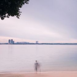 Full length of man on beach in city against sky