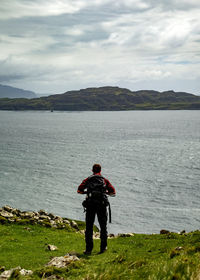Rear view of woman walking on beach against sky
