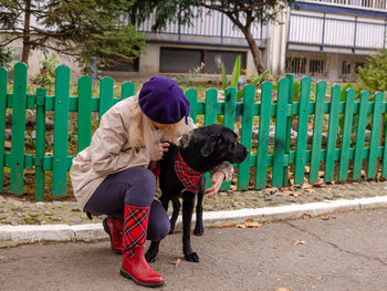 Woman hugging a big black dog - in an elegant outfit - in a walk