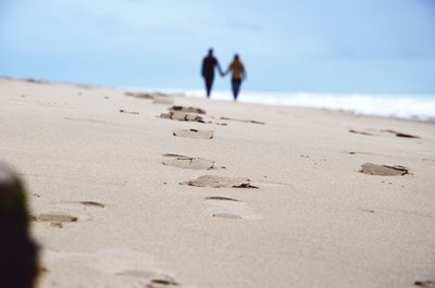 Surface level shot of couple holding hands while walking at beach