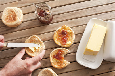 Cropped hand of man applying butter and jam on bread using table knife
