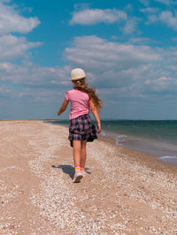 Happy child in straw hat running jumping having fun on empty autumn beach blond girl walking on sand