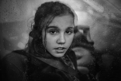 Portrait of girl seen through wet window