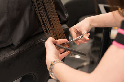 Cropped hands of hairdresser cutting woman hair