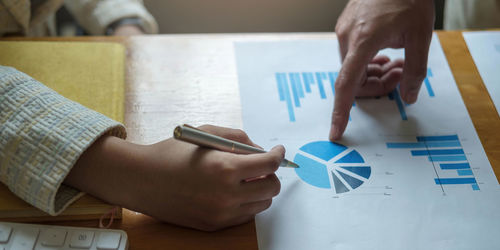 High angle view of man holding paper with text on table