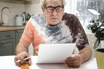 Senior man checking calculating personal finance at home, feeling stress from money problem