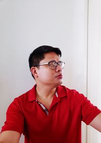 Portrait of young man looking away against wall