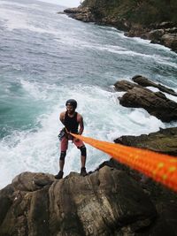 Man rock climbing against sea