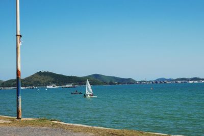 Sailboat sailing on sea against clear sky