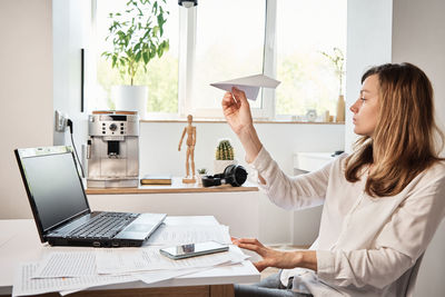 Woman plays with paper plain at home office. procrastinate at remote work