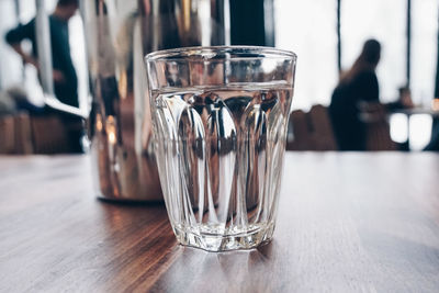 Close-up of drinking glass on wooden table at cafe