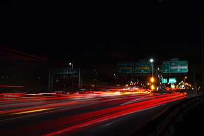 Light trails on road against sky at night