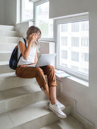 Woman with laptop sitting on staircase