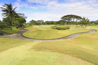 Footpath on golf course against sky