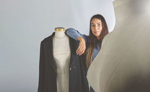 Portrait of young woman standing against wall