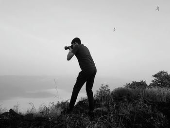 Full length of man using mobile phone against clear sky