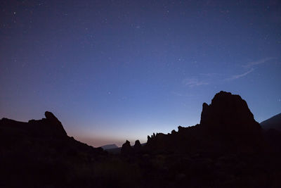 Low angle view of silhouette mountain against sky at night