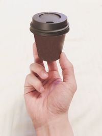 Close-up of hand holding disposable cup