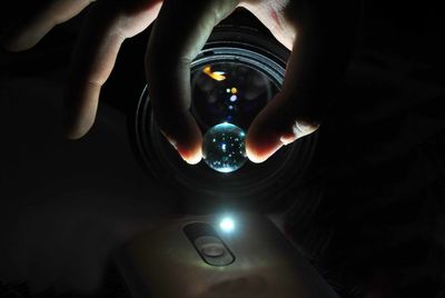 Close-up of hand holding marble in front of camera lens