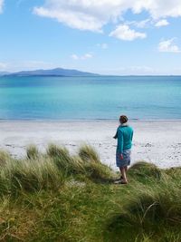 Rear view of man standing on beach against sky