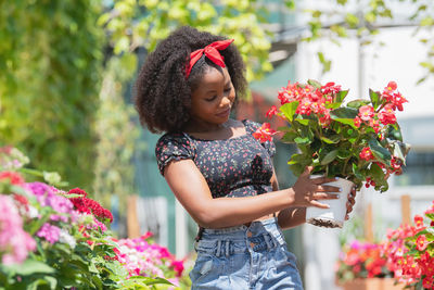 Happy girl holding flower standing against plants
