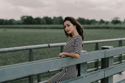 Young woman smiling while standing against railing