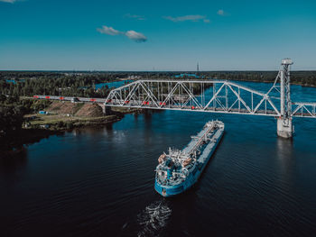 Train on the bridge over the river and cargo ship on the river