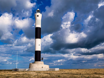 Dungeness lighthouse by sea against sky