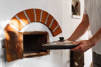 Midsection of man cooking in traditional oven 