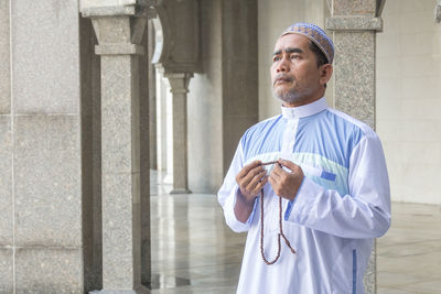 Man praying while standing in mosque