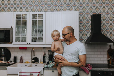 Father carrying toddler at home