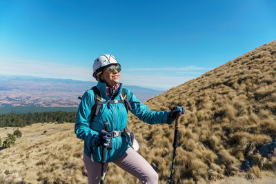 Smiling woman trekking against sky