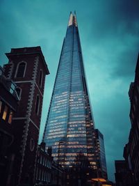 Low angle view of skyscrapers against cloudy sky