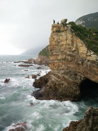 Scenic view of cliff by sea against sky