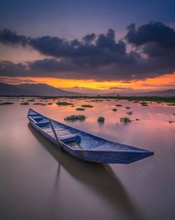 Boat moored in sea against sky during sunset