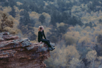 Side view of woman sitting on rock