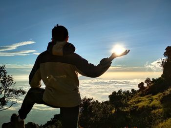 Rear view of man standing against sky during sunset