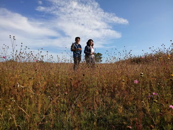 Friends standing on field against sky