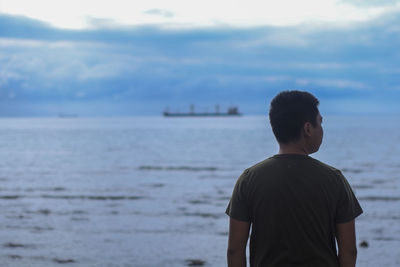 Rear view of man looking at sea against sky