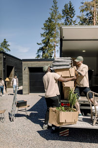 Delivery men picking cardboard boxes from truck during sunny day