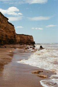 Rock formation on beach against sky