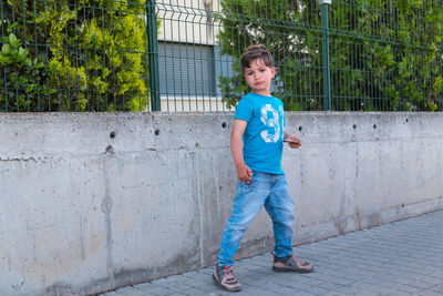 Portrait of boy standing on footpath