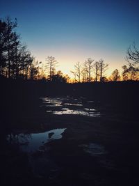 Silhouette bare trees on landscape against clear sky during sunset