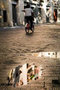 Man riding bicycle on street against building in city