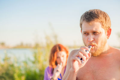 Young man smoking cigarette against woman