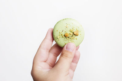 Close-up of hand holding apple against white background