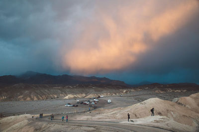 People on desert against sky during sunset