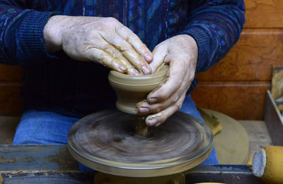 Craftsperson shaping pot on pottery wheel